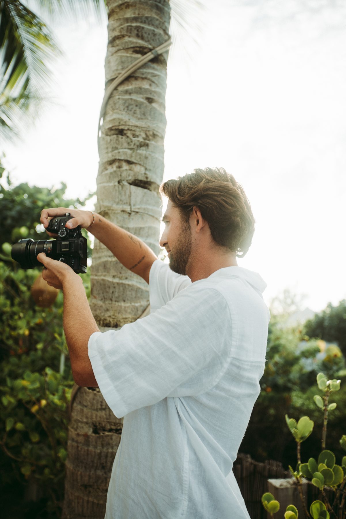 Mathias Marty, appareil photo en main, sous les palmiers